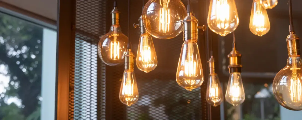 Quelques ampoules au plafond. Les ampoules sont de tailles et de couleurs différentes. La scène est chaleureuse et accueillante.