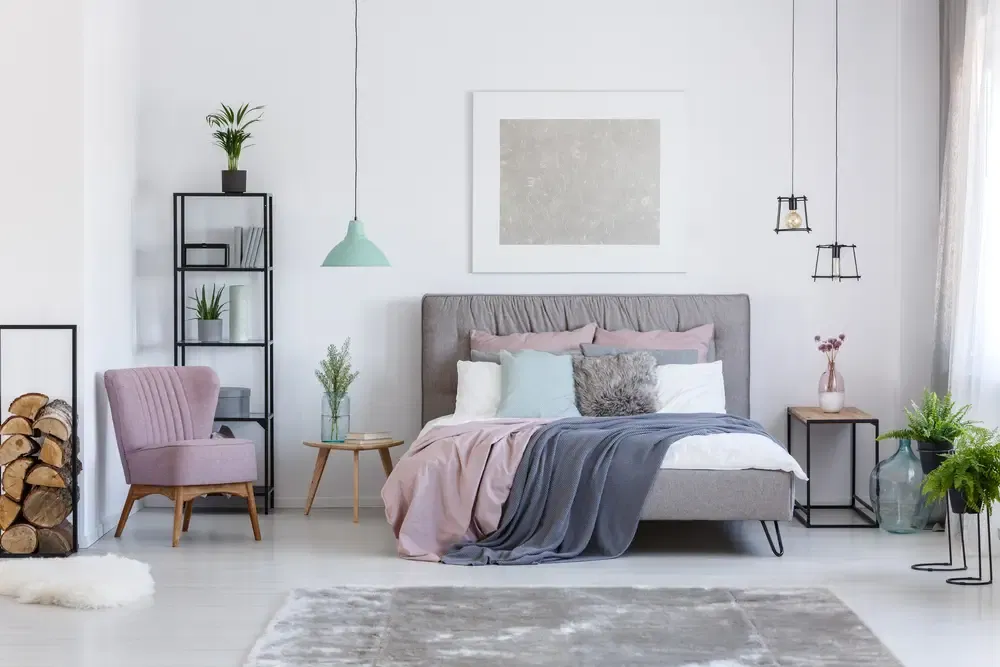 Confortable chaise rose poudreuse à côté de l'étagère avec feu de bois dans une chambre pastel douce avec vases en verre décoratif.
