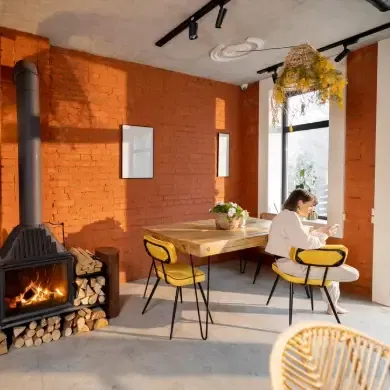 Vue intérieure d'un espace de vie confortable avec cheminée et femme assise à côté de la table à manger. Intérieur de la maison dans le style loft.