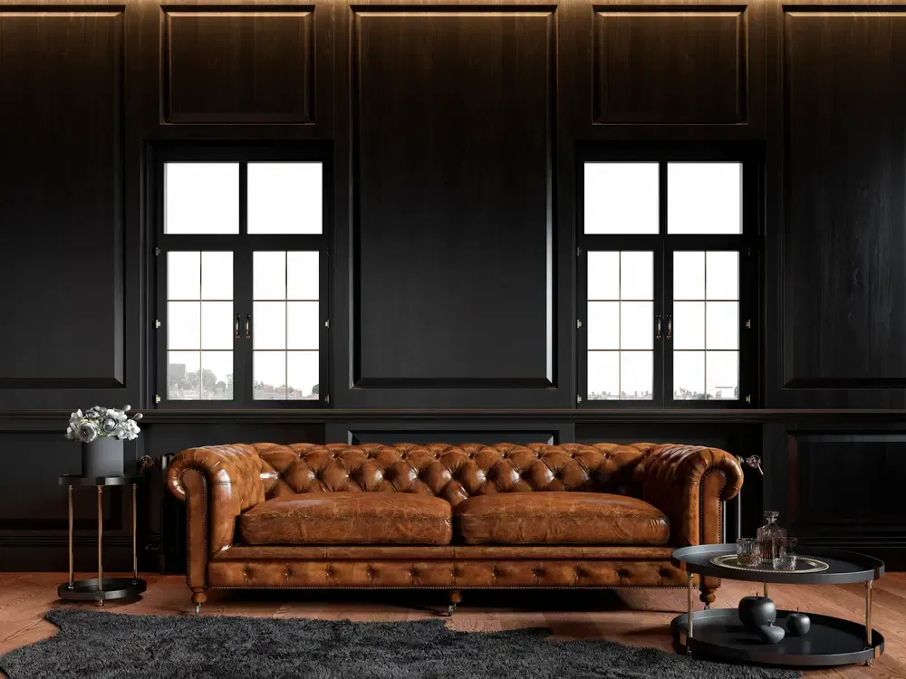 Intérieur noir loft classique avec panneau de bois, canapé chesterfield, moquette, fleurs, table basse et fenêtres. 