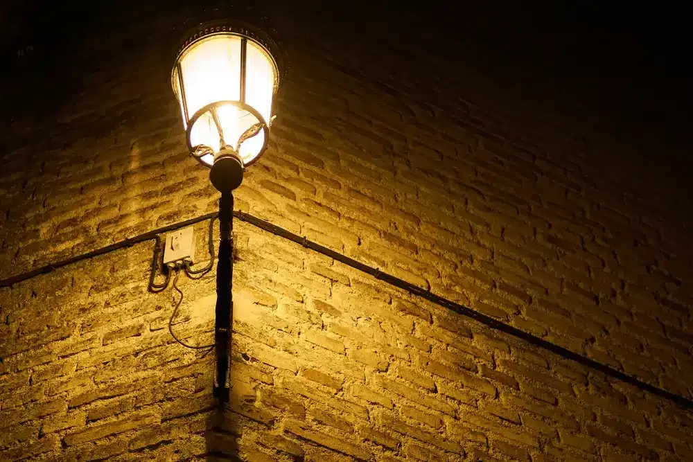 Textures d'un mur de briques et d'une lanterne s'éclairant la nuit.                           