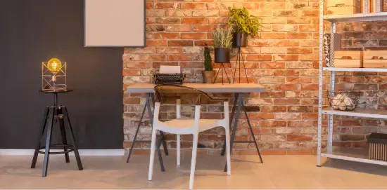 Appartement de luxe avec mur en briques, bureau, chaise, tableau, lampe, plantes.
