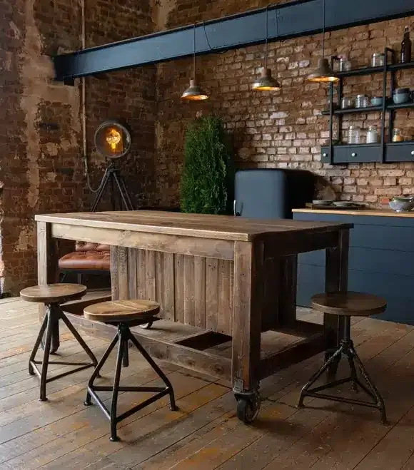 Vue latérale sur une table en bois et spacieuse cuisine industrielle loft au décor vintage et armoires noires.